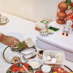 The indian prayer prepraing the worship items for thread ceremony (puja, pooja) of indian wedding event with Ganesha statue (Hindu god of wisdom)